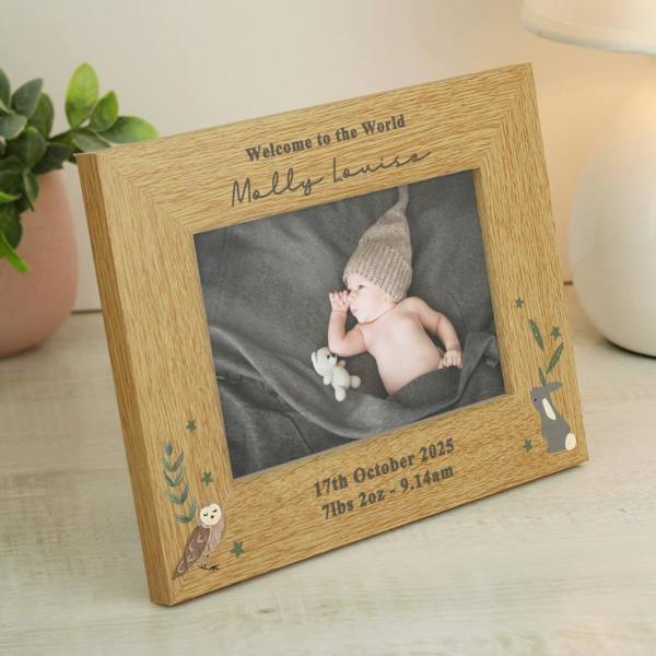 An oak veneer landscape photo frame holding a baby picture, custom engraved with Welcome to the World Molly Louise, 17th October 2025, 7lbs 2oz - 9.14am, featuring illustrated woodland animals.