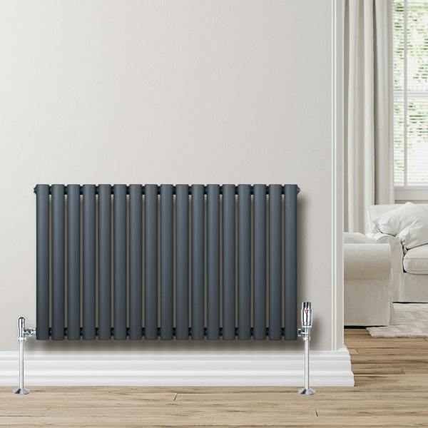 Oval single column radiator in anthracite grey, 600mm x 1020mm, with chrome valves, mounted on a light wall in a cozy room setting