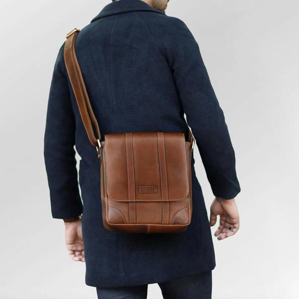 Man carrying small brown leather messenger crossbody bag for everyday use