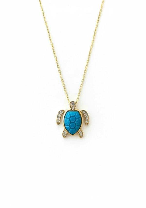 Turquoise turtle pendant necklace on a gold chain against a white background