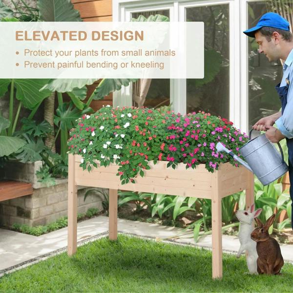 Wooden raised planter with blooming flowers while watering with a metal watering can