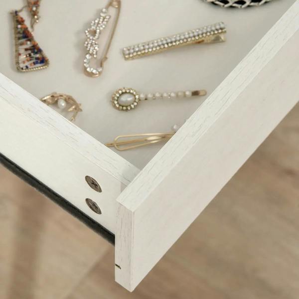 White dressing table drawer interior with jewelry and accessories, gold-toned pulls