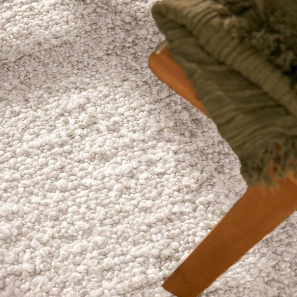 Close-up of a textured gray carpet with a green fabric edge.
