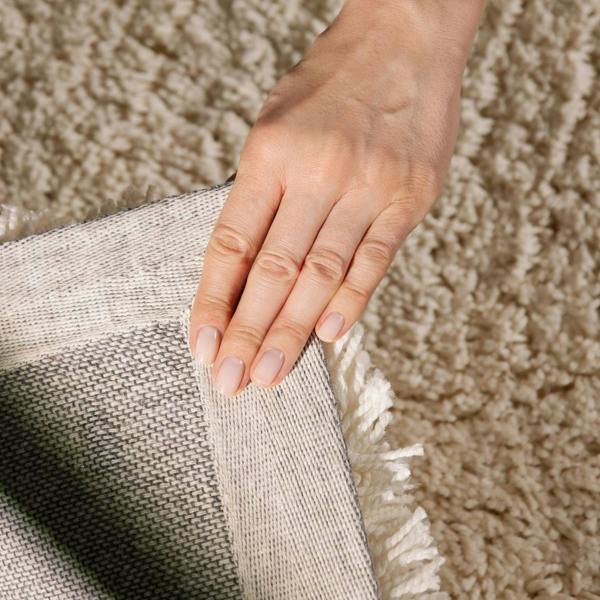 Hand touching a textured fabric against a carpeted floor