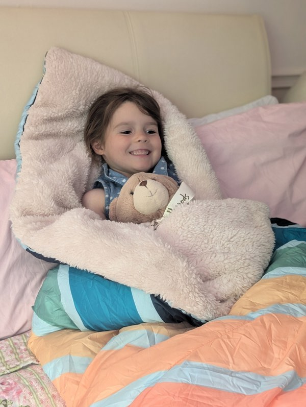 Child in bed wrapped in the tonal tree top Blanko looking all cosy with the sherpa fleece lining wrapped around them with a teddy bear. imageset:Tonal Tree Tops