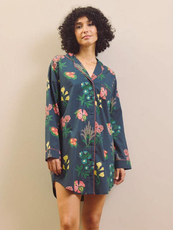 Woman wearing a navy floral patterned nightshirt against a plain background