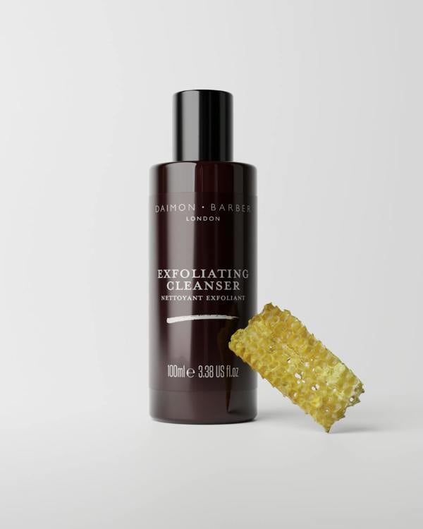 Bottle of Daimon Barber exfoliating cleanser with honeycomb on a light gray background