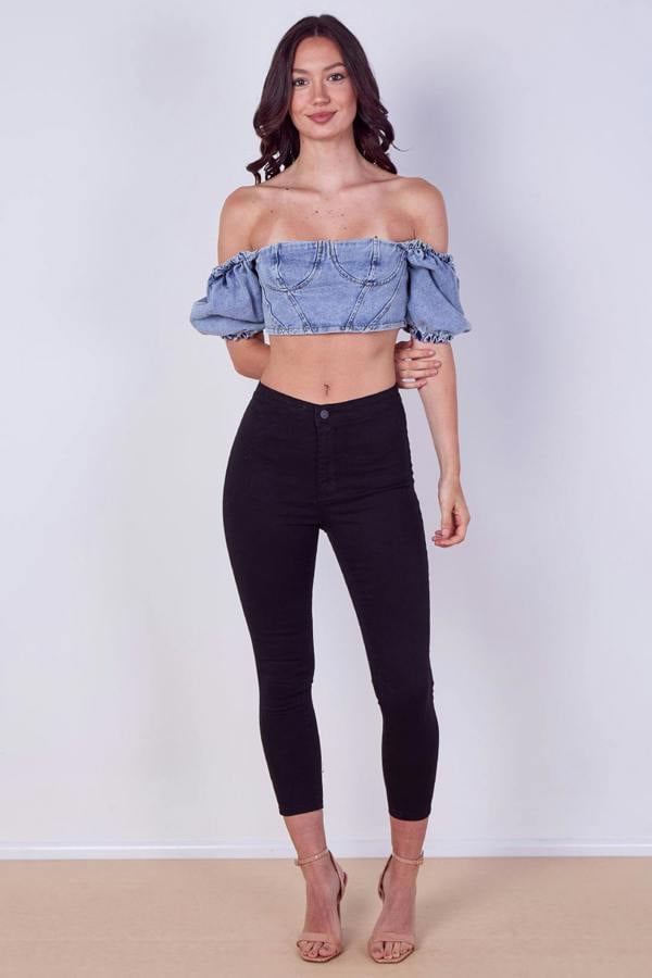 Woman wearing a denim off-shoulder top against a plain background