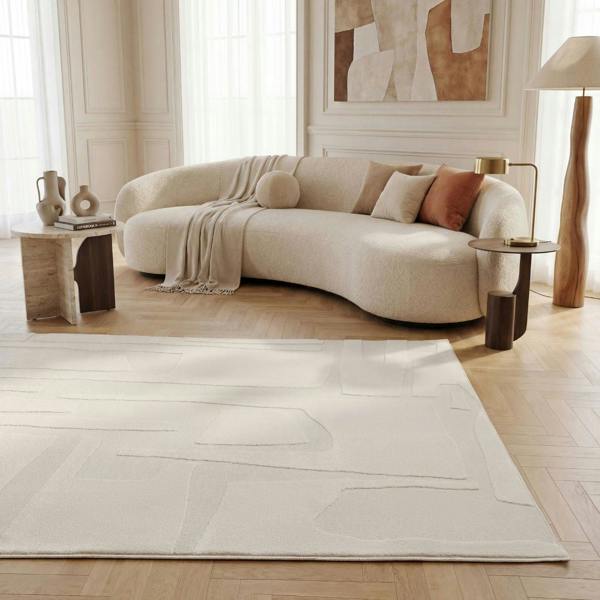 Modern living room with a curved beige sofa, wooden side tables, and abstract art on the wall.