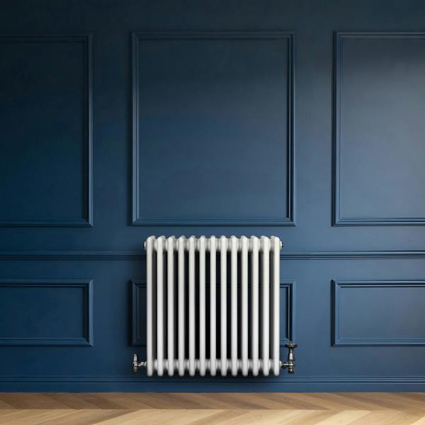 Traditional white 4 column radiator with valves, set against a deep blue wall, featuring a sleek, modern design and smooth finish