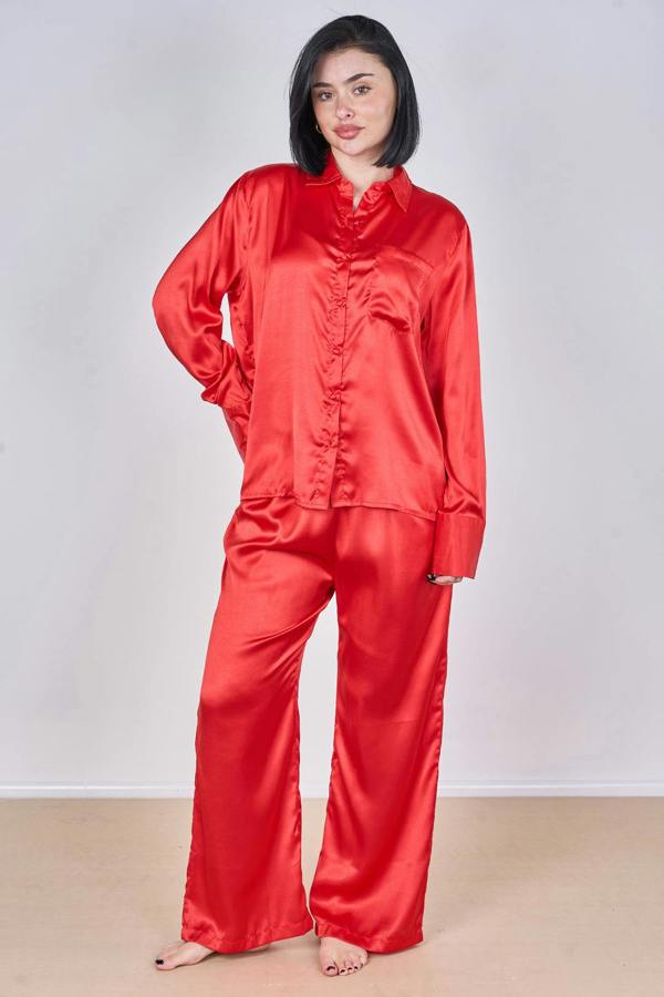 Woman wearing a red satin pajama set against a plain background
