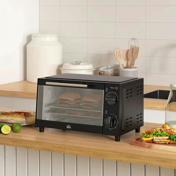 Black countertop mini oven on kitchen counter with glass door closed and control knobs.