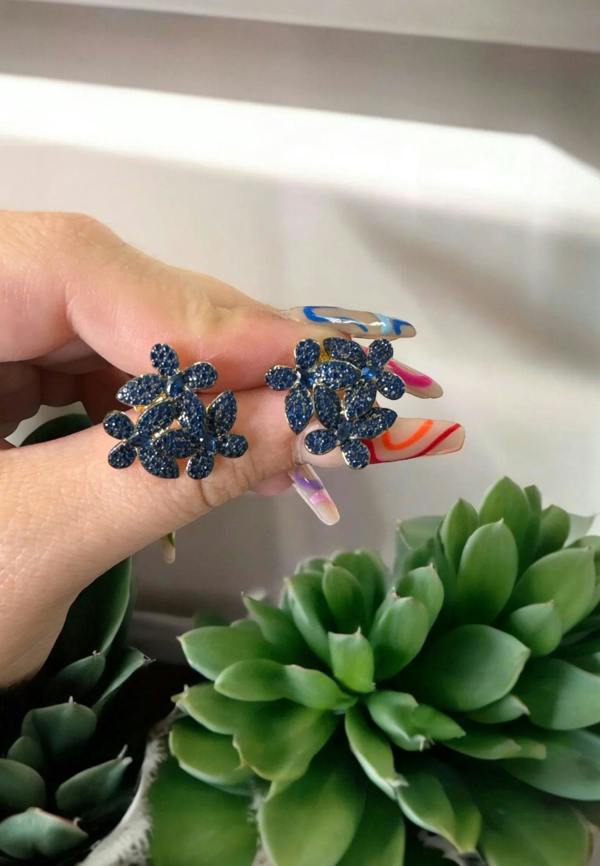 The earrings held up by a hand model.
