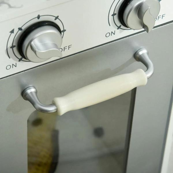White toy kitchen with front oven control knobs and a cream-colored oven handle