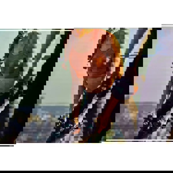 Woman exercising with dumbbells outdoors, blurred cityscape in the background