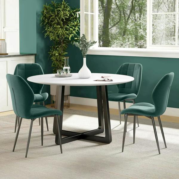 Emerald green dining chairs around a white round table with quilted backs and dark legs