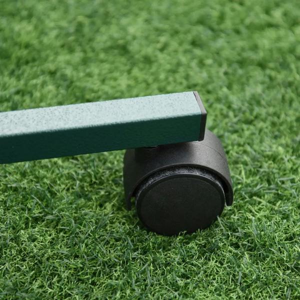 Close-up of black caster wheel on the green base of a bird perch stand