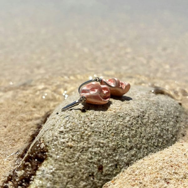 Shell earrings photographed on an exotic beach, handmade in London by LENAE featuring natural shells in coral colour.