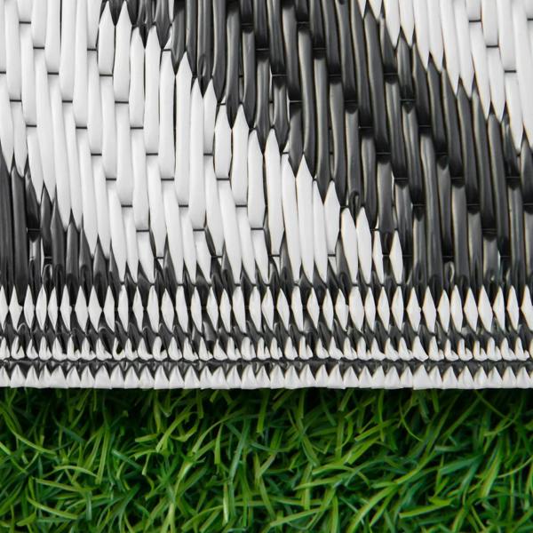 Close-up of black-and-white woven outdoor rug mat edge with braided trim