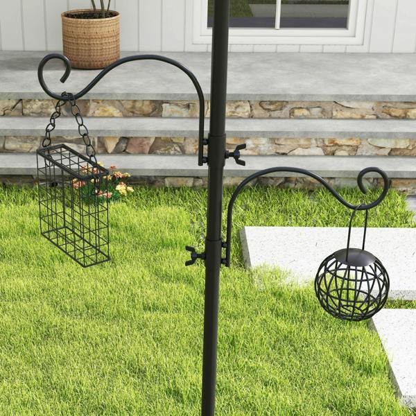 Black bird feeding station pole with hanging wire feeder and spherical feeder cup