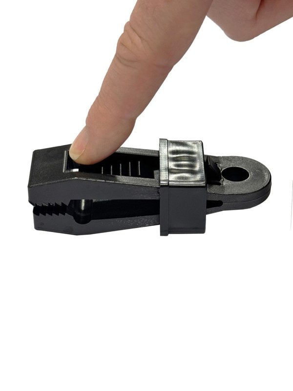 An image depicting a finger pressing the OLPRO Tent Groundsheet Pegging Clamp to demonstrate how to loosen the grip. Available in a pack of four.