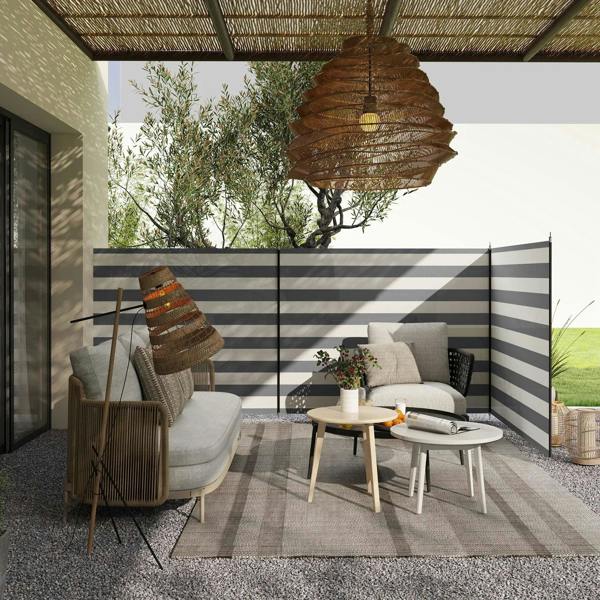 Grey and white striped outdoor privacy windbreak with steel poles, set up on patio