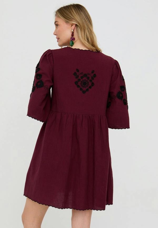 Maroon dress with black floral embroidery on a white background
