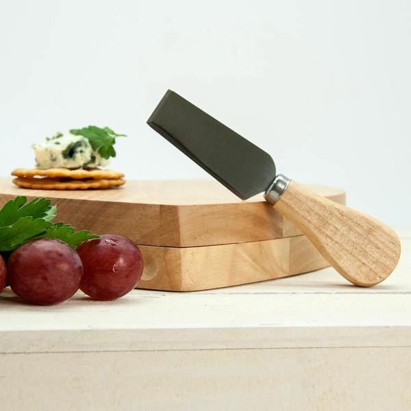 A small wooden cheese board featuring a flat cheese knife with a wooden handle, accompanied by fresh red grapes, crackers, and blue cheese garnished with parsley.