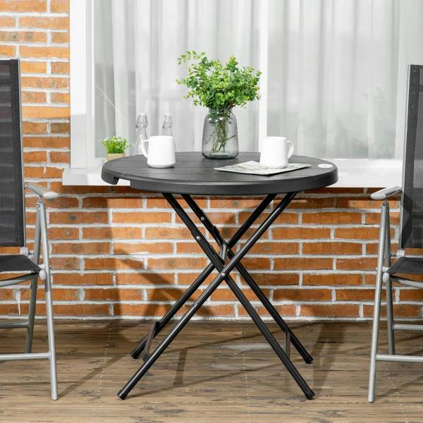 Round outdoor dining table with dark grey tabletop and black folding steel legs
