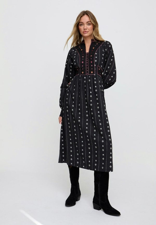 Woman wearing a black patterned dress on a white background