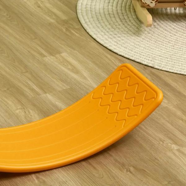 Orange curved balance board with grippy ridges, resting on wooden floor