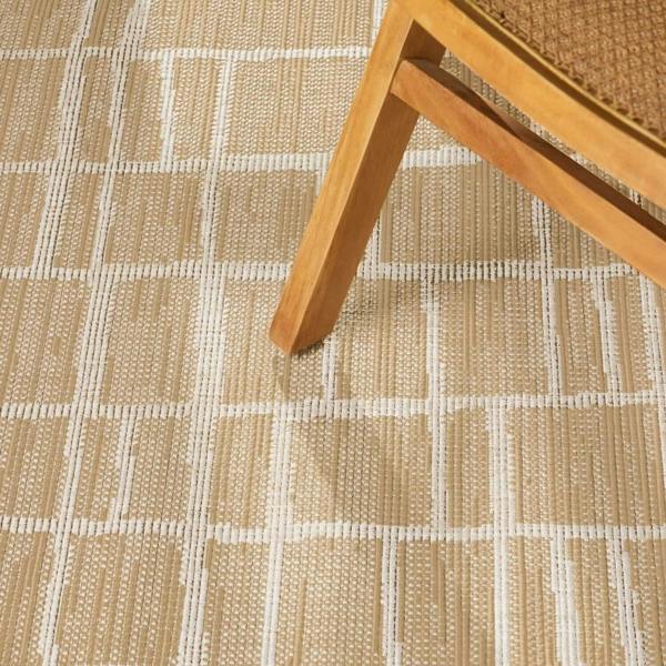 Close-up of a textured beige and white checkered floor with a wooden chair leg.