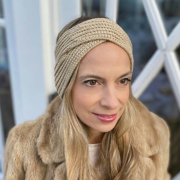 Beige knitted winter headband, soft woven texture, wide band style, warm and cosy design, twisted front detail, comfortable cold-weather accessory

