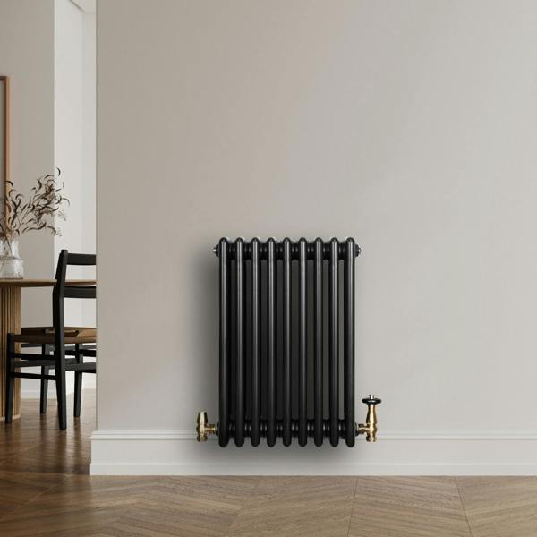 Traditional black 4 column radiator with brass valves, featuring a sleek design, mounted on a light-colored wall in a modern interior setting