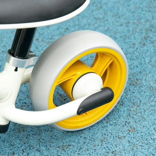 Close-up of a children's balance bike yellow wheel and white fender