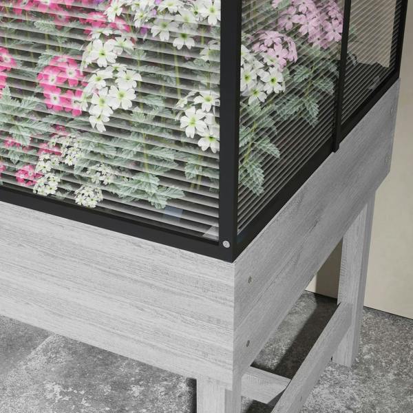 Grey raised garden bed corner with slatted mesh side and flowering plants inside