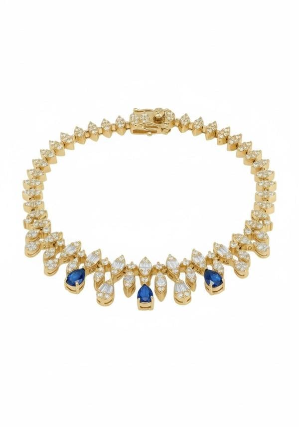 Gold bracelet with blue and clear gemstones on a white background