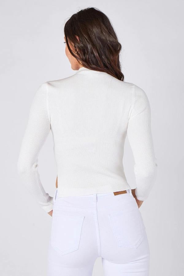 Person wearing a white long-sleeve top and white pants on a plain background