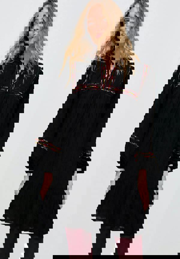 Woman wearing a black dress with red embroidery on a white background