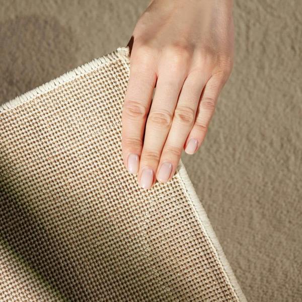 Hand holding a textured beige fabric against a neutral background