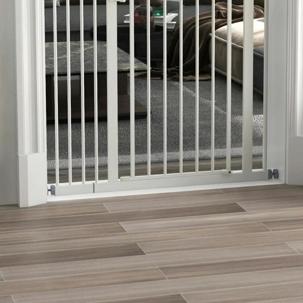 Close-up of white pet gate lower base and vertical bars over tile flooring
