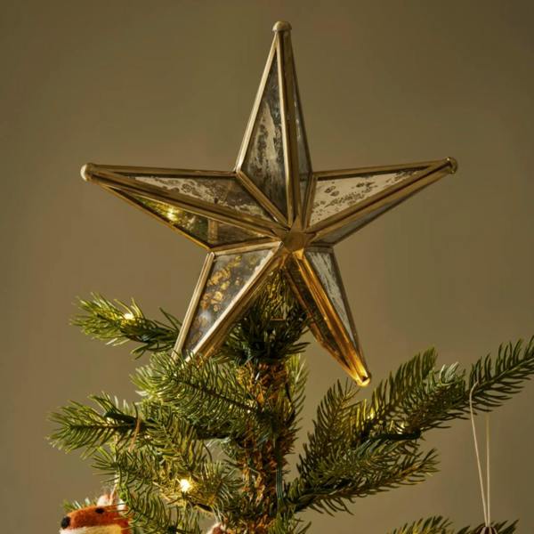 Windermere antique brass and mirrored glass star tree topper by Abode Home & Gifts sitting securely on a lit Christmas tree.