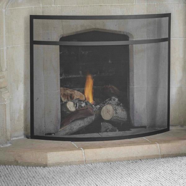 Black steel curved mesh fire screen placed in front of a stone fireplace with burning logs.