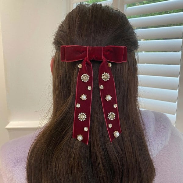 Velvet bow hair clip, deep red velvet fabric, long ribbon tails, adorned with pearl and crystal embellishments, vintage-inspired style, elegant jewelled decorative accessory for brunette hair
