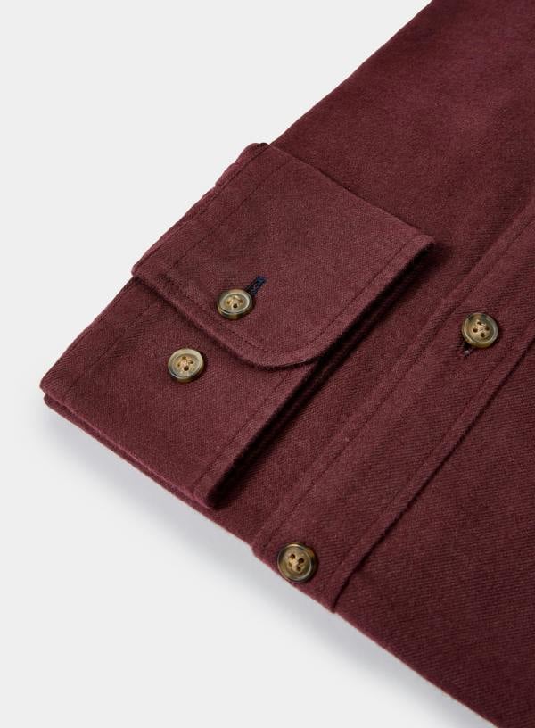 Close-up of a burgundy shirt with buttons on a light gray background