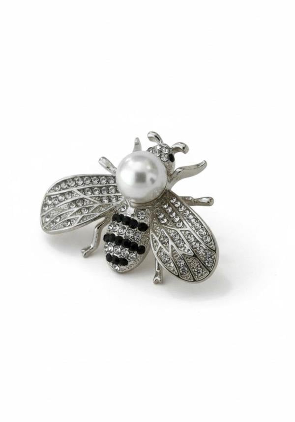 Bee-shaped brooch with pearl and black gemstones on a white background