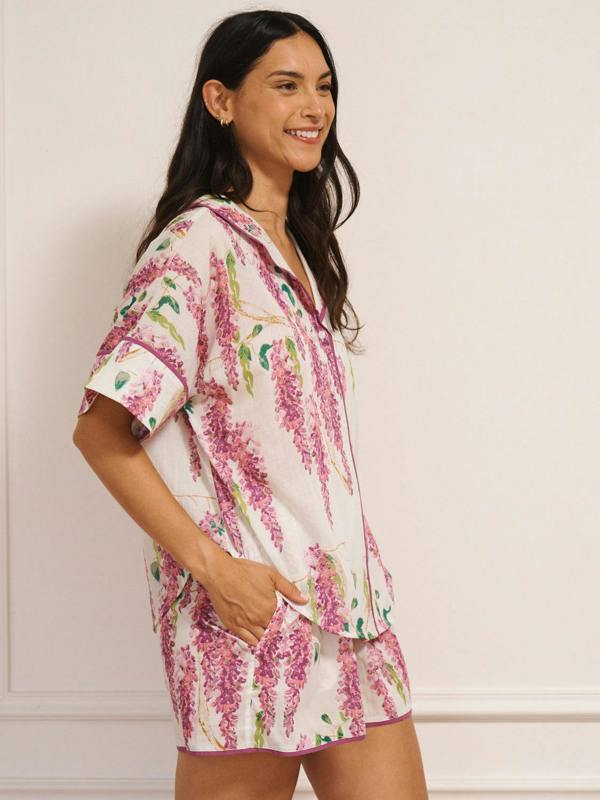 Model wearing white cotton voile oversized shortie pyjamas with pink wisteria print, short-sleeve shirt and elasticated waist shorts with pockets.