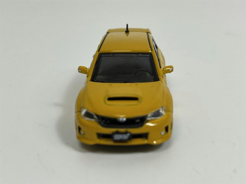 a yellow toy car on a white surface