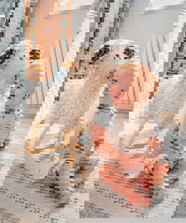 Little boy sat on floor in nursery next to lambert rocking sheep 