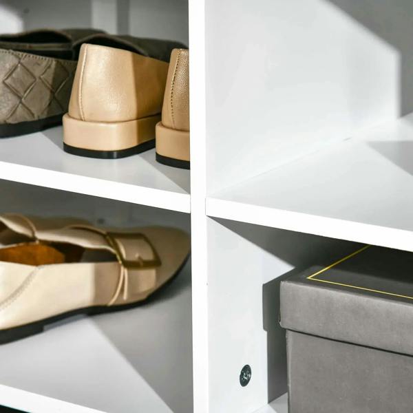 White shoe cabinet cubbies holding beige shoes with black soles and side partition